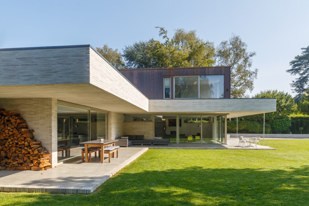 A beautiful shot of a modern home from the back garden, featuring sliding doors.